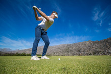 Wide Angle View Of A Golfer Teeing Off From A Golf Tee On A Bright Sunny Day On A Golf Course In South Africa.