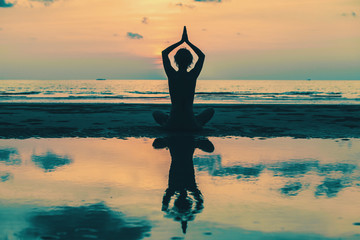 Wall Mural - Yoga Silhouette. Woman on the beach with reflection in water.