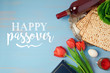 Jewish holiday Passover Pesah greeting card with seder plate, matzoh and tulip flowers on wooden background