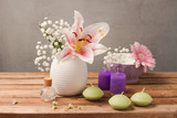 Fototapeta Na ścianę - Spa and wellness concept with flowers in vase and candles on wooden table over rustic background