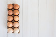 Fresh eggs in carton package on white wood background
