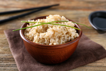 Wall Mural - Bowl with brown rice on wooden table background