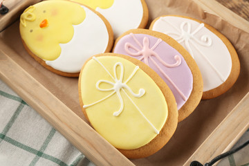 Wall Mural - Wooden tray with creative egg shape Easter cookies on table