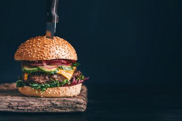 mouth-watering, delicious homemade burger used to chop beef. on the wooden table. The burgers are inserted knives.