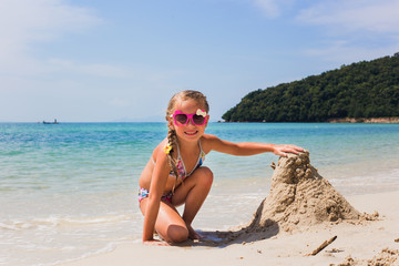 cute little girl playing with sand on tropical beach