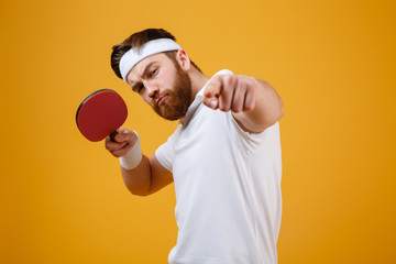 Wall Mural - Young sportsman holding racket for table tennis while pointing.