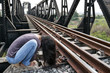 Desperate woman alone beside railway in foetal position, depression, sadness, suicidal crisis
