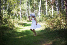 A Lovely Girl In A Hat And Sunglasses Walks Through The Forest On A Summer Sunny Day. She Runs And Dances.