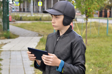 Wall Mural - The teenage boy's portrait with the tablet computer in hands on the street.