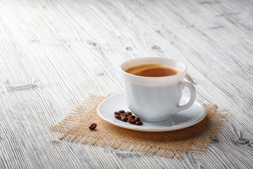 Poster - Coffee cup and beans on a white wood background.