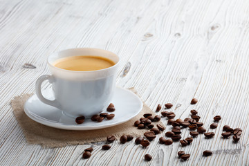 Poster - Coffee cup and beans on a white wood background.