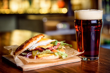 Hamburger and dark beer on a pub background.