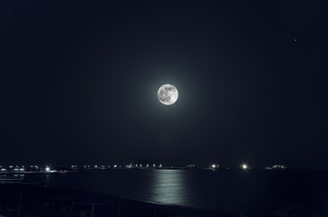 Wall Mural - A beautiful night landscape of full moon over dark water with reflections on it