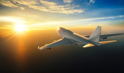 Wall Mural - airplane flying over the sea during sunset