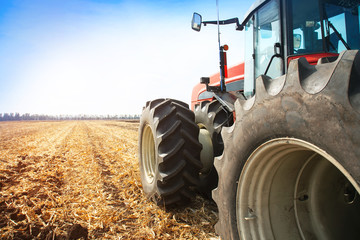 Modern red tractor in the field close-up.