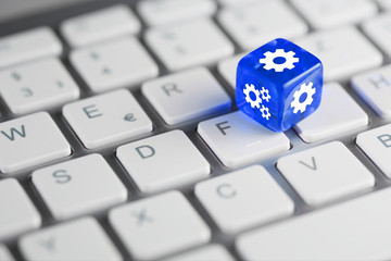 Blau farbener / blauer Würfel auf Tastatur mit Zahnräder / Einstellungen Setup Konfiguration