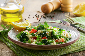 Wall Mural - Traditional Moroccan couscous with broccoli, tomato and other vegetables on a plate. Eastern meal for healthy lunch on a table.