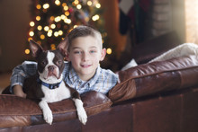 Portrait Of Young Boy Sitting On Sofa With Pet Dog