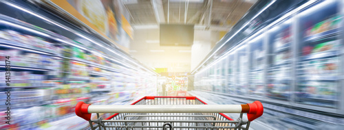 Cuadros en Lienzo Supermarket aisle with empty red shopping cart