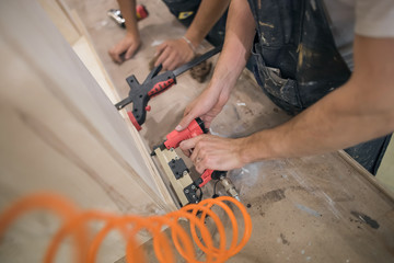 two men with gun nails. carpenters work