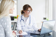 © sepy - Doctor and her patient. Shot of a middle aged female doctor sitting in front of laptop and consulting with her patient.