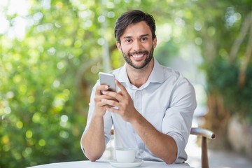 Man smiling while using his mobile phone n the restaurant