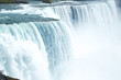 Blue water Waterfall flowing over edge at Niagara Falls with mist and foam