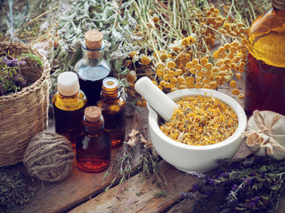 Wall Mural - Tincture bottles, mortar of dried marigold flowers and healing herbs on wooden board. Herbal medicine.