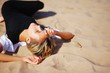 © raisondtre - Young sexy blond girl in black dress is lying with closed eyes in the sand