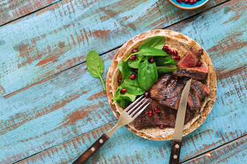 Wall Mural - Plate with grilled steak, spinach, pomegranate on wooden blue table