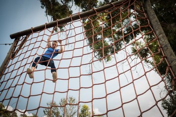 Wall Mural - Woman climbing a net during obstacle course