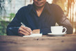 © Johnstocker - Young man writing on a notebook working on a rustic wooden table.