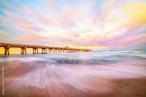 Pier lit by the rays of the sun at sunset, dawn on the ocean shore Fototapet