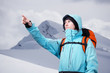 © Vasily Merkushev - The mountaineer pointing at peak, standing against a winter mountain landscape.