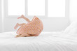 © Lisa Tichané - Little girl rolling on a white bed with her feet in the air