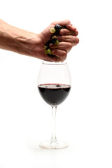 Strong male hand squeezing wine from grapes to glass