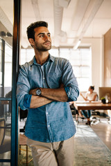 Wall Mural - Young man standing at door while colleagues in background