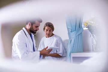 Wall Mural - Male doctor showing digital tablet to female senior 