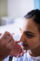 Hands of male doctor examining female patient eyes