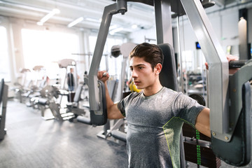 Wall Mural - Hispanic man in gym sitting on bench, working out with weights