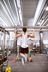 Sticker - Hispanic man in gym doing pull-ups on horizontal bar.