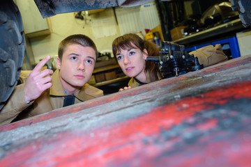 Wall Mural - Young mechanics looking at underneath of vehicle