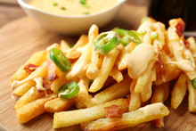 Wooden Board With Tasty Cheese Fries And Sauce, Closeup
