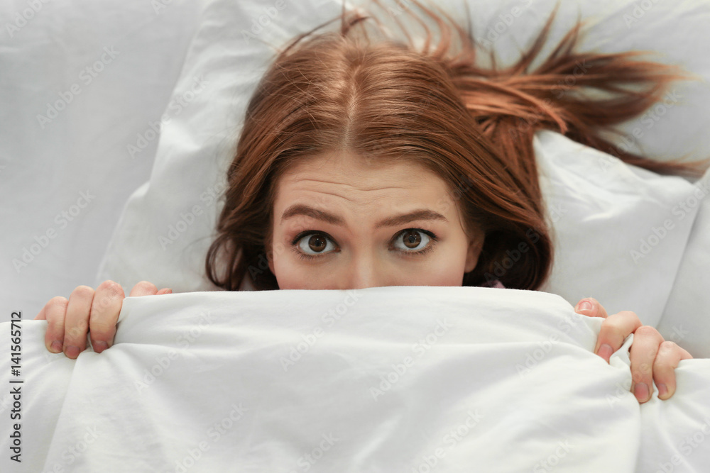 Young woman with sleep disorder lying in bed at home