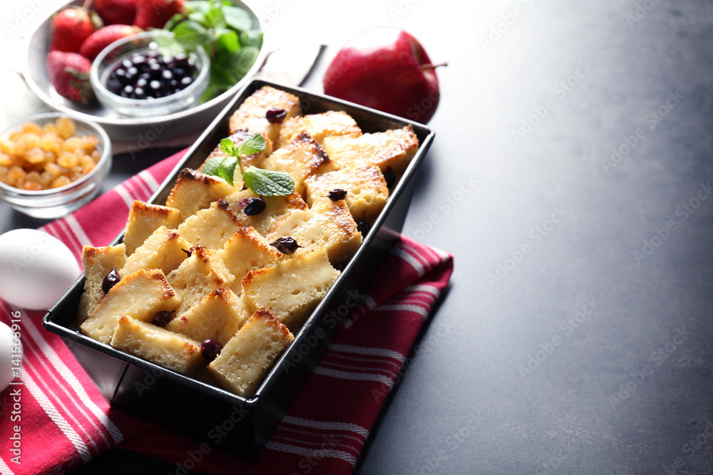 Delicious bread pudding with currant in baking dish on kitchen table