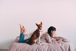 © onewithahalf - Hipster girl lounging in bed with coffee