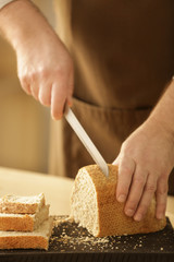 Wall Mural - Hands of man cutting bread on kitchen table