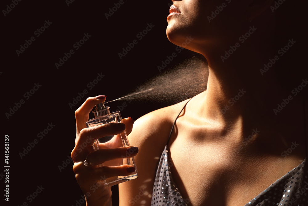 Beautiful young woman with bottle of perfume on dark background - obrazy, fototapety, plakaty 
