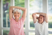 Senior Couple Performing Stretching Exercise At Home