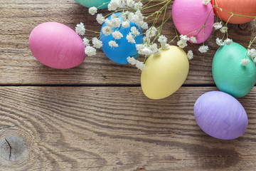 Easter eggs and white flowers on old wooden background.